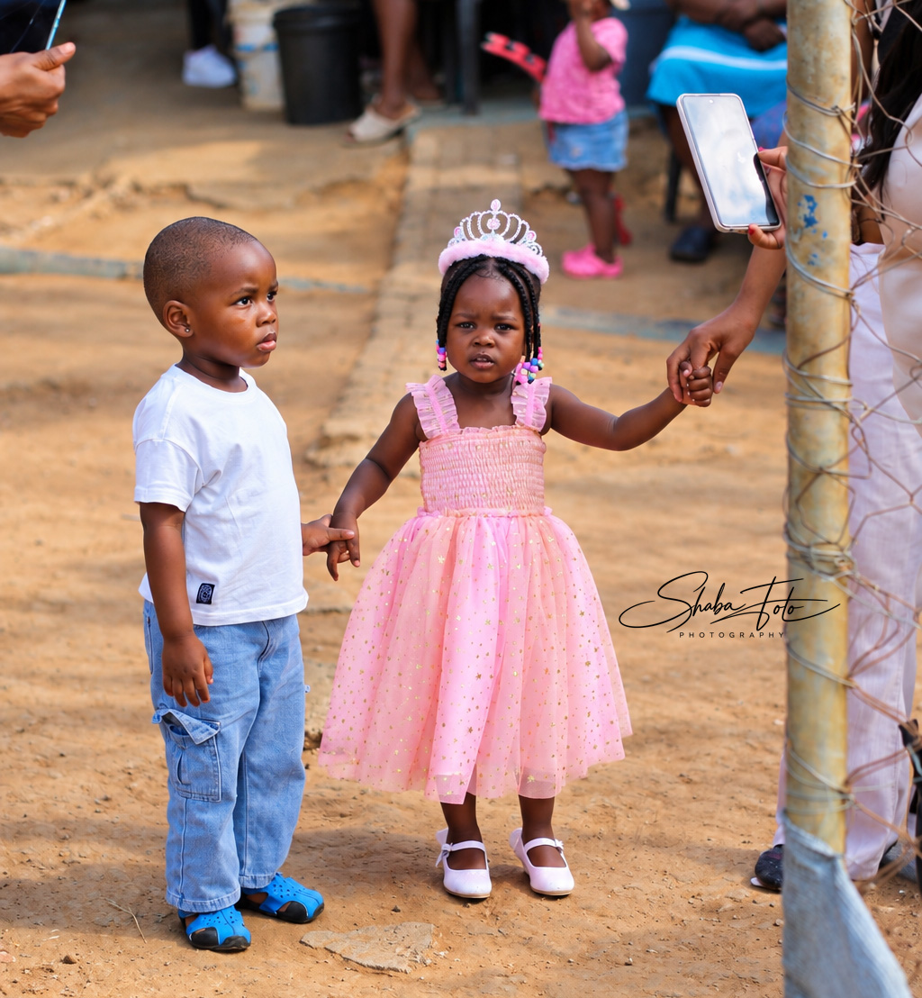 Two children standing together at an outdoor celebration
