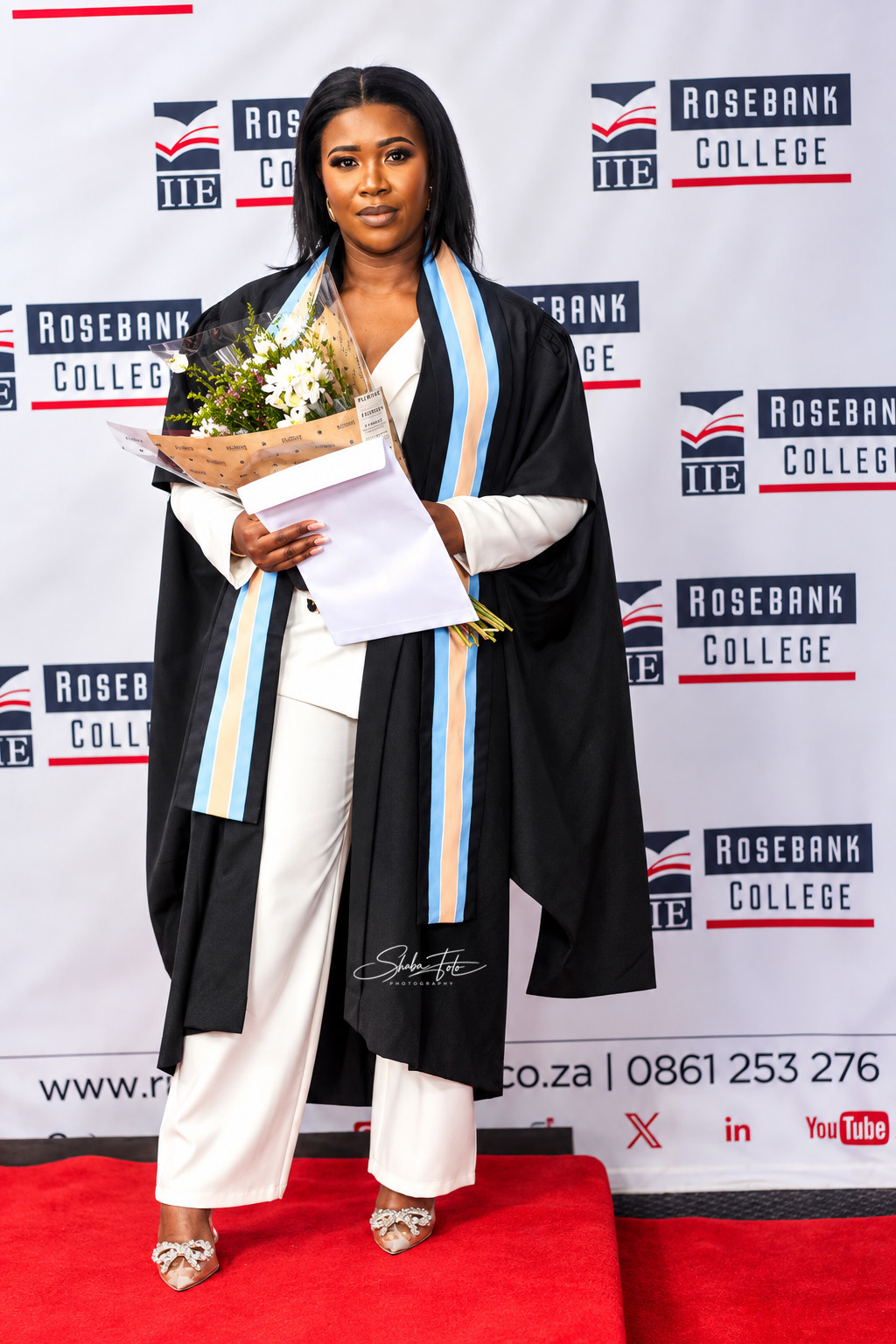 Graduate holding a bouquet in front of a Rosebank College backdrop