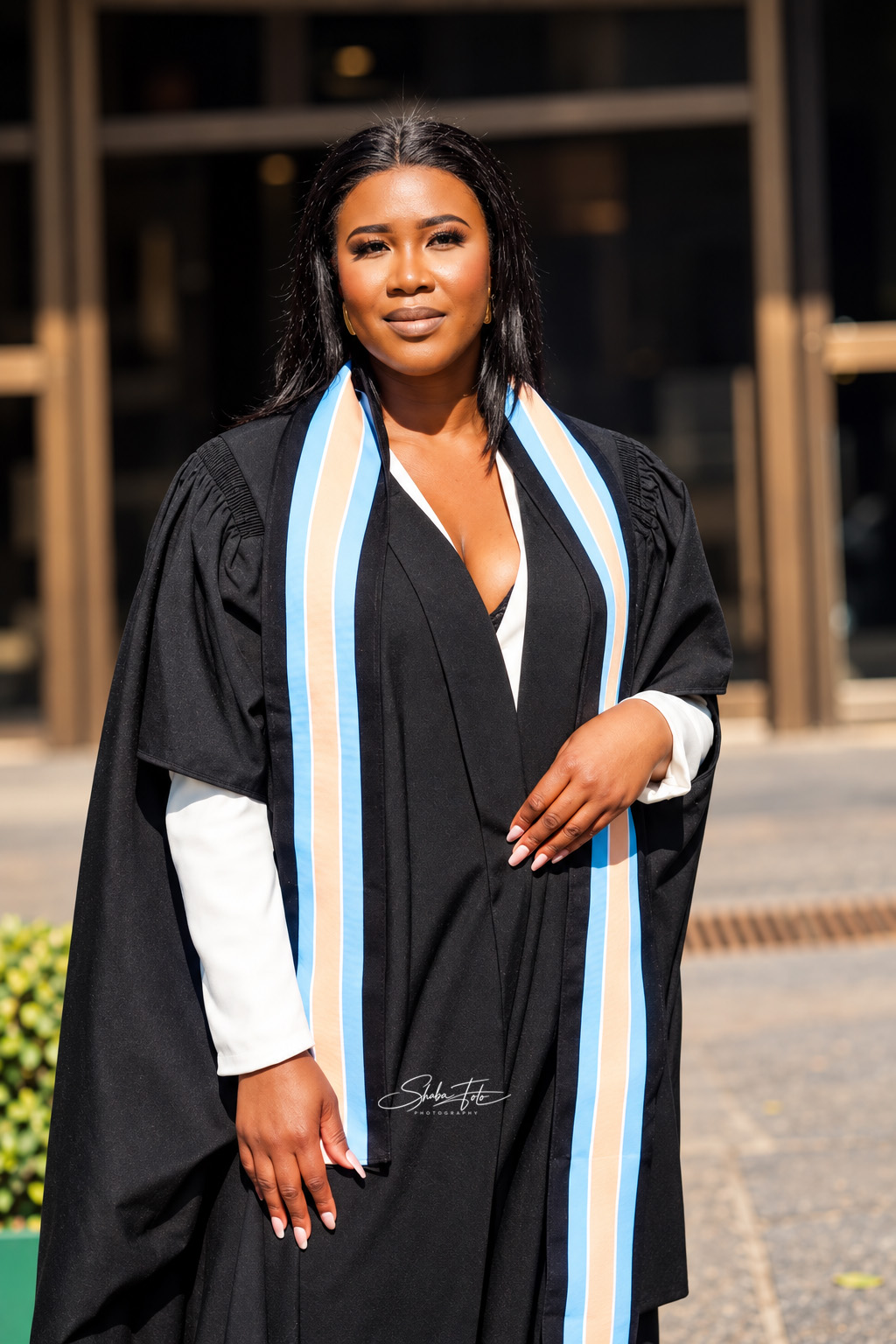 Graduate wearing a black gown with a blue and white stole